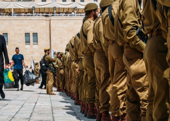 צעיר חרדי צועד ליד חיילים | צילום: שאטרסטוק